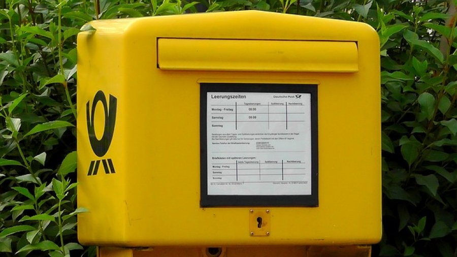 Mit Weihnachtspostkarten „Frohe Weihnachten“ wünschen - Ein gelbes Schild mit schwarzem Text - Briefkasten
